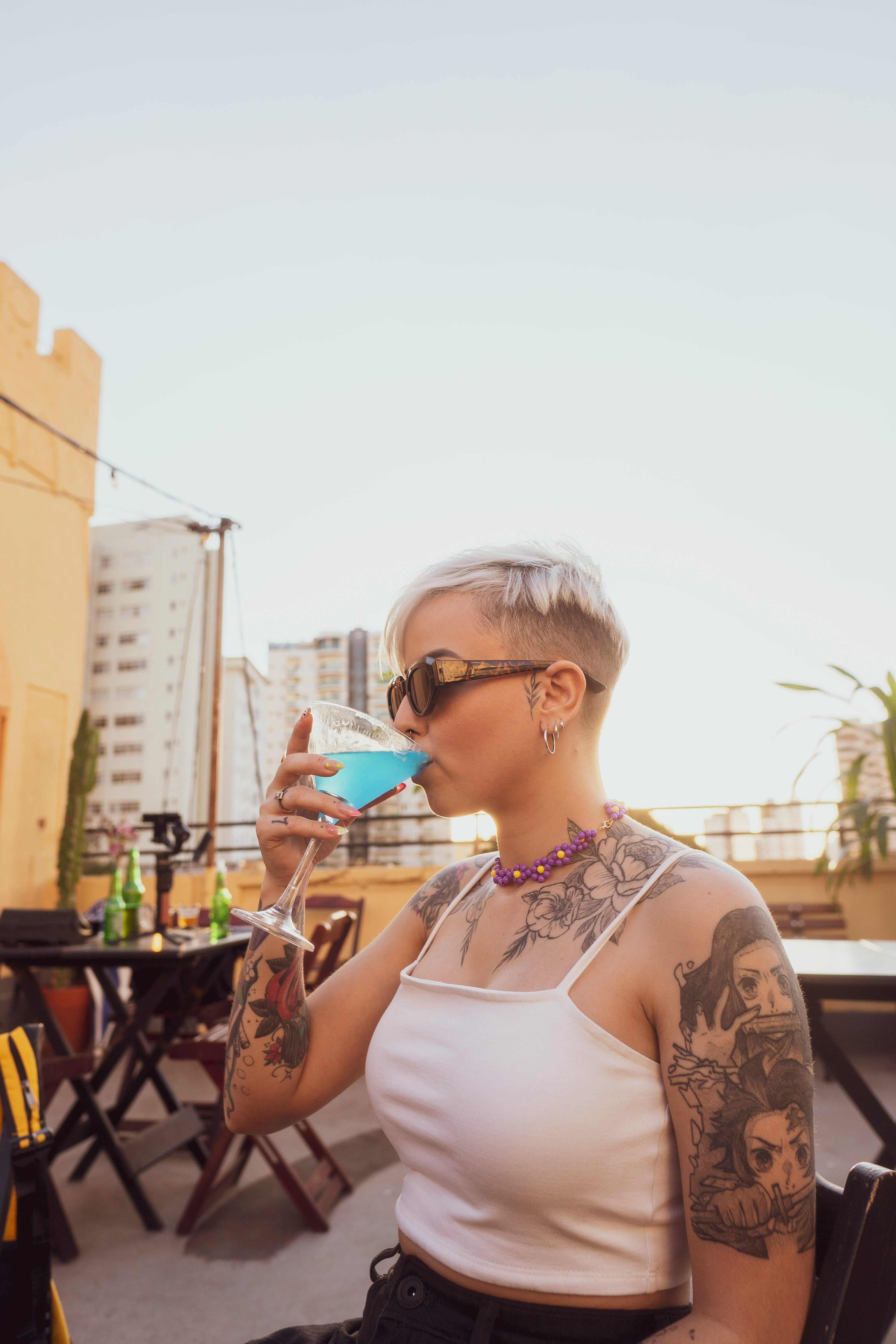 woman in white tank top wearing sunglasses holding cup